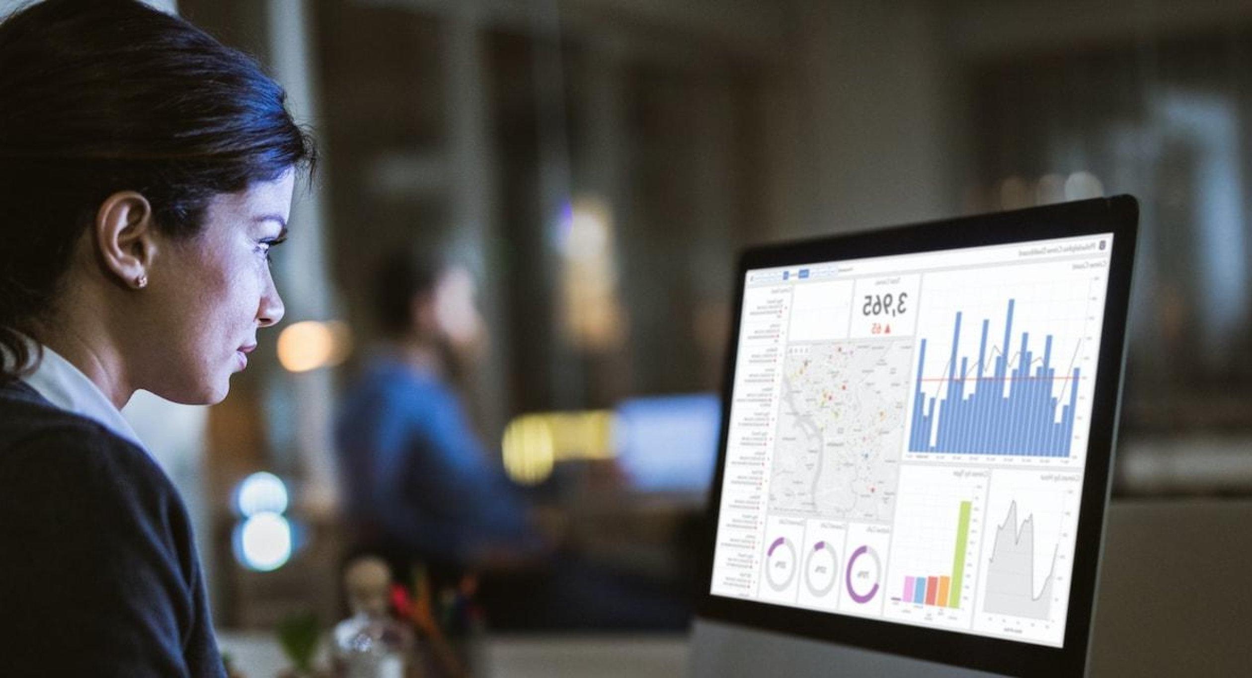 Woman lokoing at business data on computer screen.