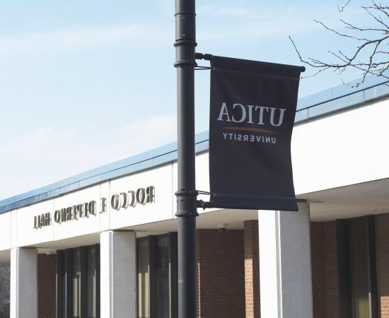 A blue Utica University banner hangs outside Rocco DePerno Hall.