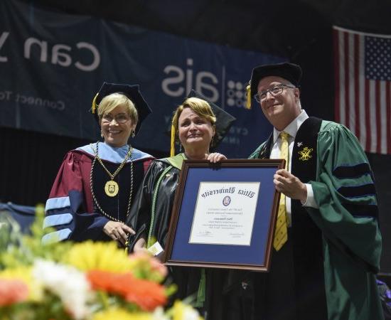 职业治疗教授Mary Siniscaro站在教务长Todd Pfannestiel和校长Laura casmento之间, holding her award at the 2023 本科 Commencement Ceremony.